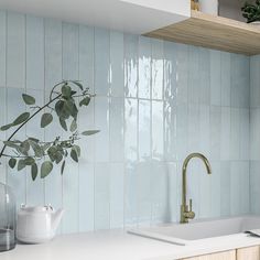 a kitchen with blue tiles and white countertops has a gold faucet on the sink