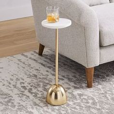 a small table with a glass on it sitting in front of a couch and chair