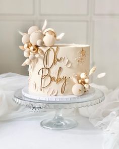 a white cake with gold lettering and flowers on top is sitting on a glass platter