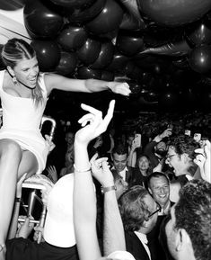 a woman in a white dress is on the shoulders of a crowd