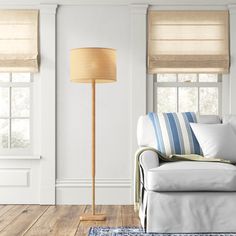 a living room with white walls and wooden flooring, two lamps on either side of the couch