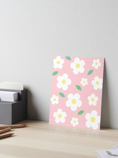 a pink and white flowered card sitting on top of a desk next to a pencil box