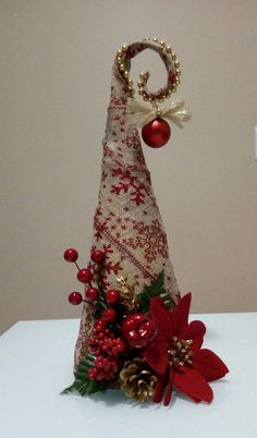 a knitted christmas cone with poinsettis and pine cones on the top