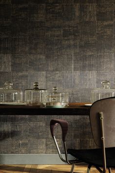 a table with glass jars on it next to a chair and wallpapered wall