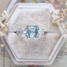 an engagement ring with blue and white stones in it on top of a velvet box