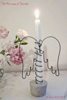 a candle holder with an angel design on it and a flower in the vase next to it