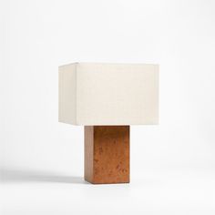 a wooden table lamp with a white linen shade on the top and bottom part of it