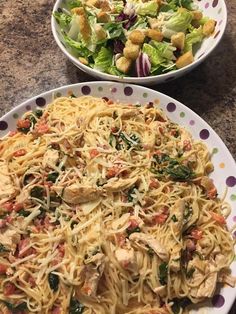 two plates with pasta and salad on them