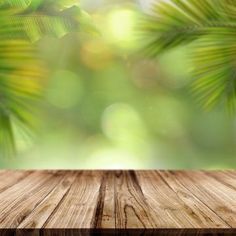 an empty wooden table in front of a blurry background with palm leaves and boke