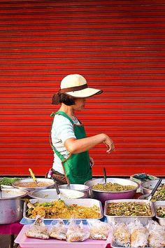 a woman standing in front of a table filled with lots of different types of food