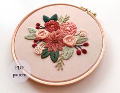 a close up of a embroidery on a hoop with flowers and leaves in the center