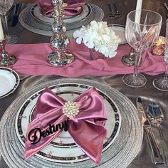 the table is set with silverware and pink napkins