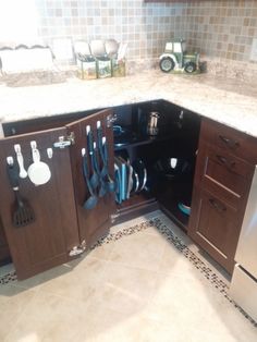 an open cabinet in the middle of a kitchen with utensils hanging from it