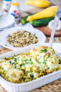 a casserole dish with broccoli, cheese and other food items on the table