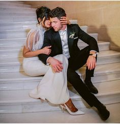 a bride and groom are sitting on the stairs