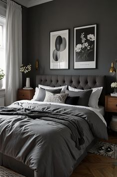 a bedroom with gray walls and bedding, two pictures on the wall above it