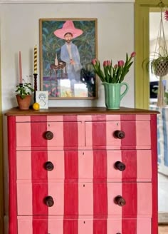 an old dresser painted pink and red with stripes