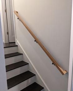 there is a wooden hand rail on the wall next to some black and white stairs