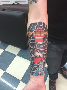 a man's arm with a lighthouse tattoo on it