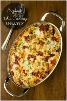 a casserole dish with meat and cheese in it on a wooden table next to two silver spoons