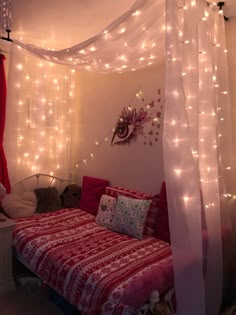 a bed covered in white lights next to a red and white blanket on top of a bed