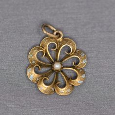 "Sweet Victorian Enamel and Pearl Flower Style Pendant Charm in 14k Yellow Gold This sweet old pendant harkens to times long ago.  The piece features a scalloped floral design and the remnants of turquoise blue enamel.  The pearl center grounds the piece.  We think this makes a lovely pendant or charm.  The piece measures 1\" in height including the bail and is 3/4\" across in width.  The piece is crafted in 14k and weighs 1.60g." Yellow Gold Enamel Jewelry With Flower Charm, Victorian Flower Jewelry For Collectors, Victorian Flower Jewelry Collectible, Victorian Flower-shaped Collectible Jewelry, Victorian Flower Collectible Jewelry, Yellow Gold Enamel Flower Pendant Jewelry, Antique Gold Flower Jewelry, Gold Enamel Art Nouveau Jewelry, Art Nouveau Gold Enamel Jewelry