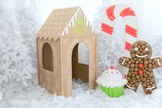 a gingerbread house, cupcake and candy canes are displayed in the snow