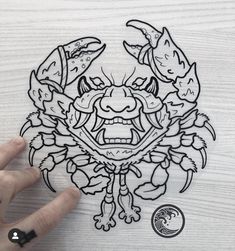 a hand holding up a sticker with an image of a crab on it's face