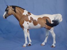 a brown and white horse standing on top of a blue background