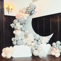 balloons floating in the air next to a large moon and clouds on top of a wooden table