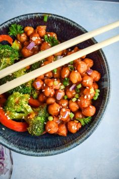 a bowl filled with broccoli and chickpeas next to chopsticks