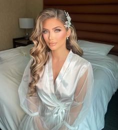 a woman sitting on top of a bed wearing a white robe