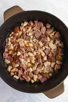 ham and potatoes cooking in a cast iron skillet on top of a white counter