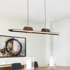 a dining room table with two lights hanging over it and candles on the table next to it