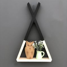 an owl figurine sitting on top of a shelf next to a vase with flowers