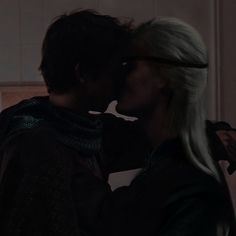 two people are kissing in the dark with their heads close to each other and one is wearing a scarf