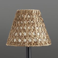 a lamp that is made out of wicker on a metal stand with a black base