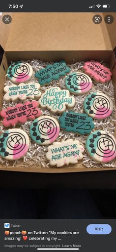 an open box of decorated cookies with happy birthday messages on them, sitting on a table