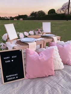 pink and white pillows sitting on top of a bed next to a wooden table with a chalkboard sign