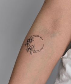 a woman's arm with a flower and crescent tattoo on the left side of her arm