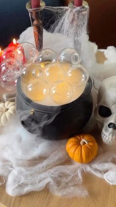 a table topped with candles and skulls on top of white fluffy cloth next to an orange pumpkin