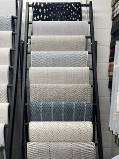 an assortment of rugs are on display in a room with white walls and black metal racks