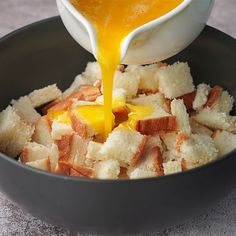 a bowl filled with bread and cheese being poured into it