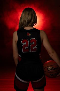 a woman holding a basketball in front of a red light with the number 22 on it