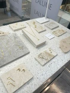 there are many necklaces and earrings on the table in front of the store window