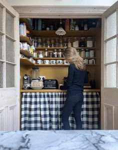 a woman standing at the counter in a kitchen