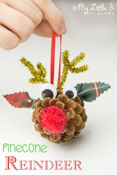 a pinecone reindeer ornament is being held up by someone's hand