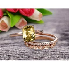 two gold rings with an oval cut yellow sapphire surrounded by smaller white diamonds and pink tulips