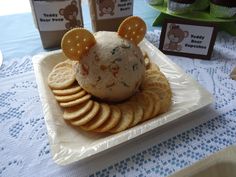 a plate with crackers and cheese ball shaped like a mouse on it, sitting on a table