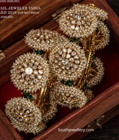 three gold and diamond brooches in a wooden box with other jewelry on display